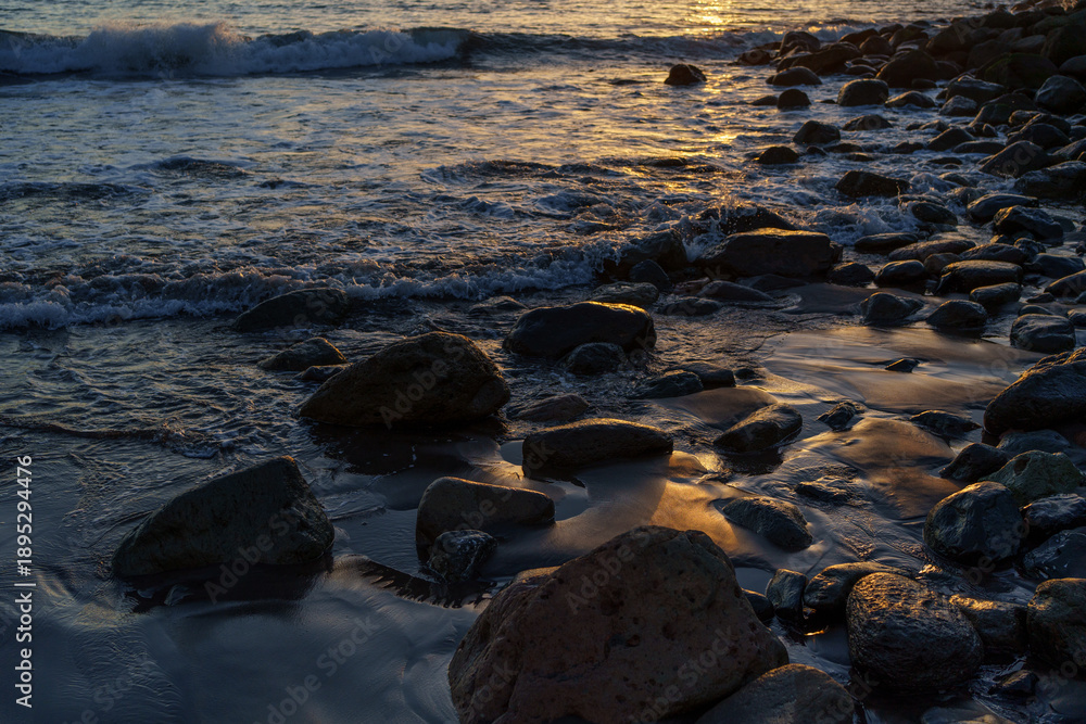 Obraz premium Waves Washing Over Coastal Rocks in Soft Sunset Light