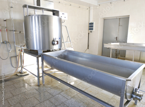 A cylindrical metal tank connected to a long rectangular bath. Dairy shop. Ripening and salting of cheeses and feta cheese. Cheese production.