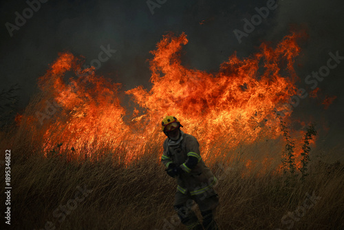 Firefighter Standing Calmly in Front of a Raging Wildfire