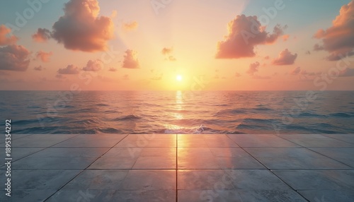 Empty concrete platform meets ocean waves at beautiful sunset. Sun sets over sea horizon with orange sky and clouds. Calm water reflects light.