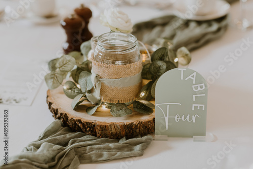 Wedding or party table centrepiece with candle and table number four, rustic, green and white
