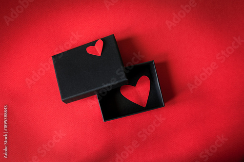 Foto Minimalist Valentine's Day composition with a black gift box and red heart on bright red background