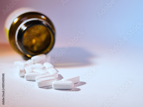 White Pills Spilled from Medicine Bottle - White oval pills spilled from an open brown prescription bottle on a clean white background. Concept for health, medication, pharmacy, and dosage.