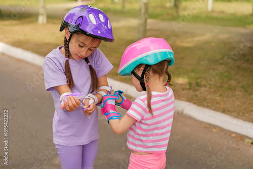 Εκτύπωση καμβά Two young girls wearing helmets and wrist guards prepare for roller skating outdoors