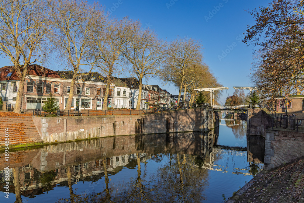 Fototapeta premium Picturesque view of the historic canal and drawbridge in Vreeswijk, Nieuwegein, with traditional houses and autumn leaves reflecting in the water.