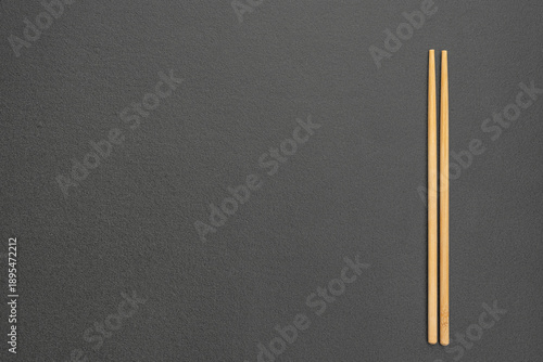 Horizontal textured black background with bamboo chopsticks