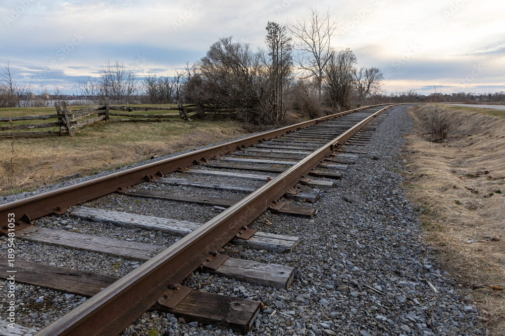 Obraz premium Railway tracks running into the distance in early spring. Rural railroad line.