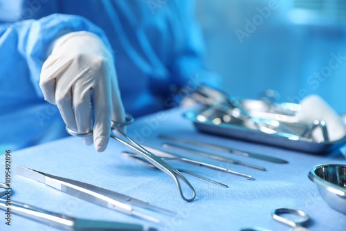 Tableau sur toile Doctor with different surgical tools at table in hospital, closeup
