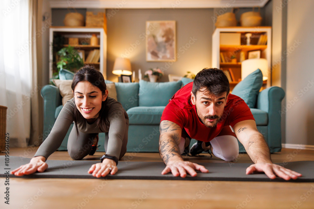 Fototapeta premium Couple doing back stretching out while working out at home