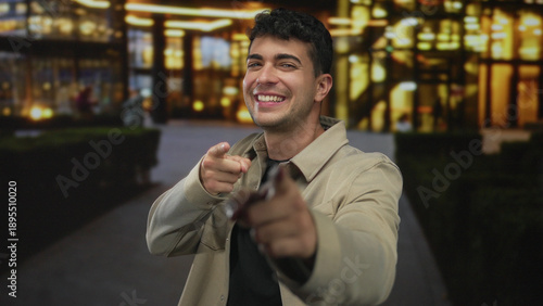 Bilde på lerret Man holds finger while pointing toward city skyline by a young hispanic at night with a smile outdoors in an urban area