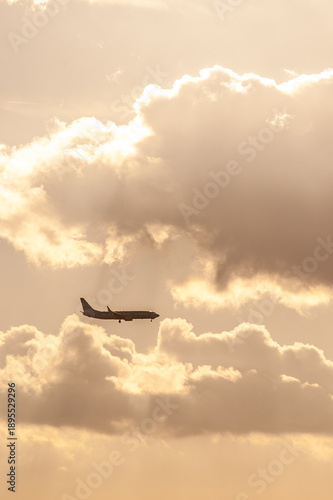 Silhouette of passenger airplane flying through dramatic sunset clouds