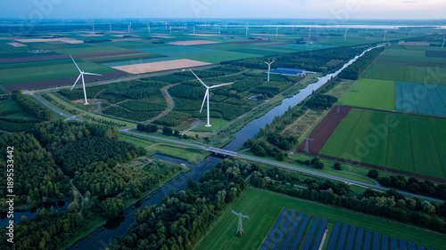 Aerial View of Wind Farm with Turbines Over Agricultural Fields and Canal Demonstrating Renewable Energy Infrastructure in Rural Landscape