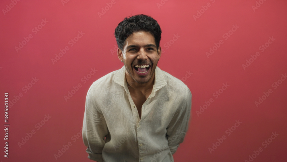 Obraz premium Man smiling showing teeth and laughing with clenched hands wearing linen shirt in studio; joy confidence.