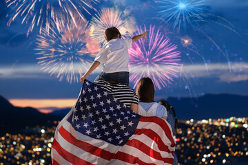 Family with american flag celebrating national holiday and enjoying fireworks over city