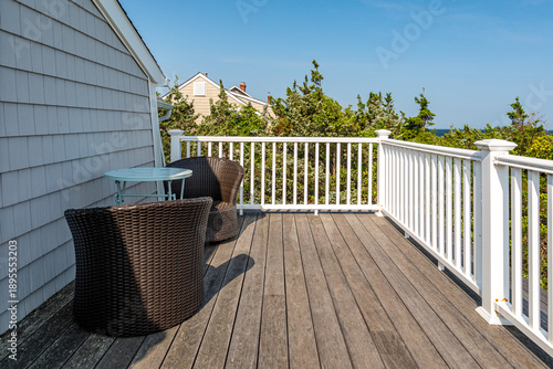 Foto Coastal home deck with outdoor seating, wooden floor and white railing overlooki