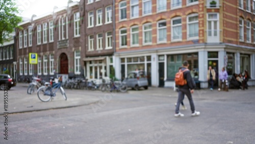 Fotografie Blurred man with backpack walking in european city square surrounded by historic buildings with bokeh bicycles, creating an outdoor urban ambiance