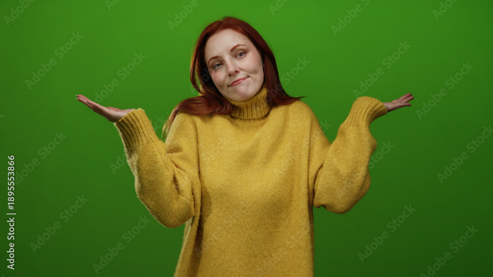 © Krakenimages.com - Woman redhead wearing yellow sweater stands against vibrant green wall showcasing a thoughtful expression with closed eyes while gesturing with her hands in a peaceful manner.