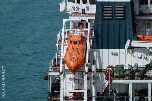 Orange enclosed lifeboat mounted on ship deck