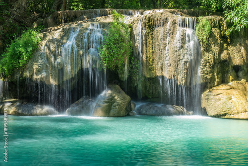 Erawan Falls, the famous seven-layered waterfall in Erawan Falls National Park In Kanchanaburi, Thailand. Water cascading over boulder into turquoise pool below. 
