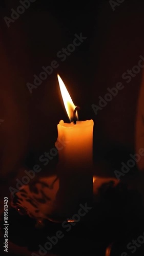 Candle flame glowing softly in dark environment on a plate  