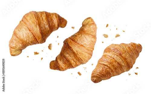 Fotografie three golden croissants floating in the air with scattered crumbs against a transparent background, creating a dynamic and delicious composition