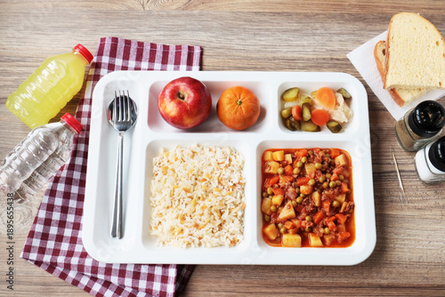 Fotografie Traditional Turkish meal with ground meat with peas, potatoes, rice, pickles, and fruits in white portion food tray