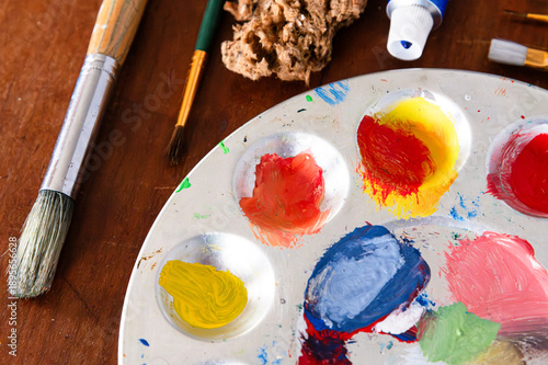 Top view of a paint pallette and paint supplies, including brushes