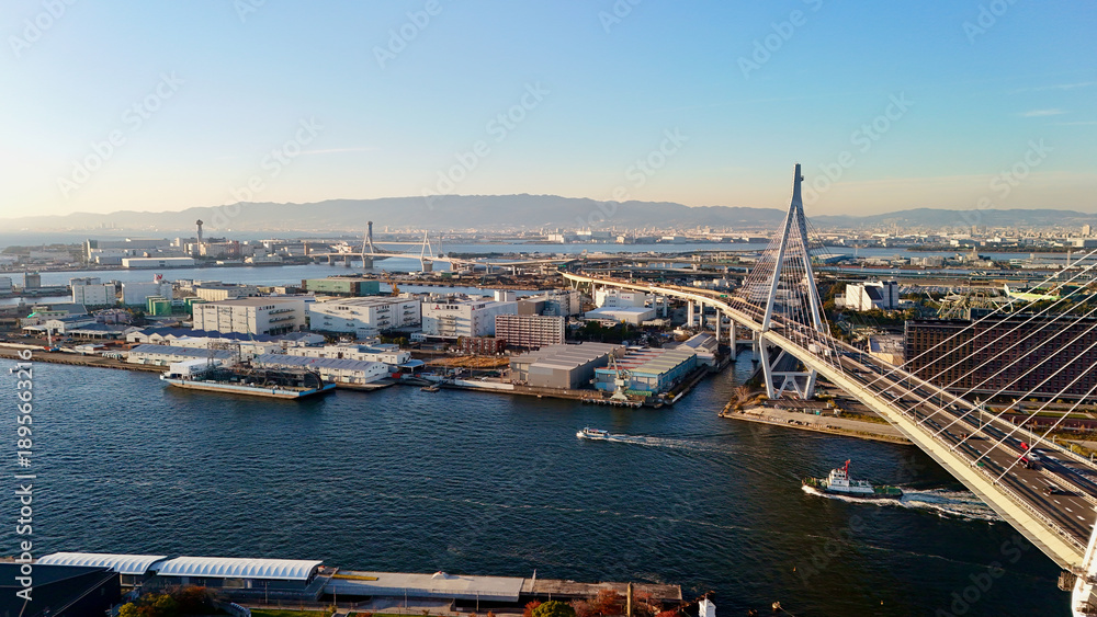 Obraz premium Osaka, Japan at sunset: Aerial Drone View of Tempozan Bridge, Tempozan Wharf, Harbour, Port of Osaka, Harbour, Osaka Bay, Ferris Wheel, City Skyline, Evening Colours in Konohana and Minato Ward