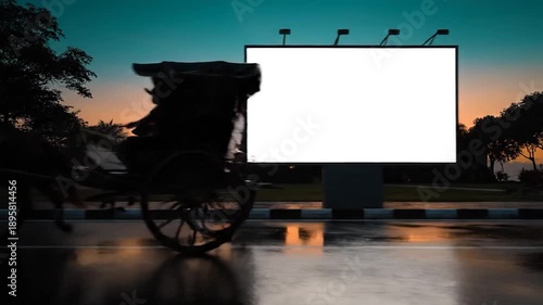 Empty urban billboard at dusk on a reflective wet street, an old traditional carriage silhouetted, ideal for advertising display or mock-up in a vibrant city