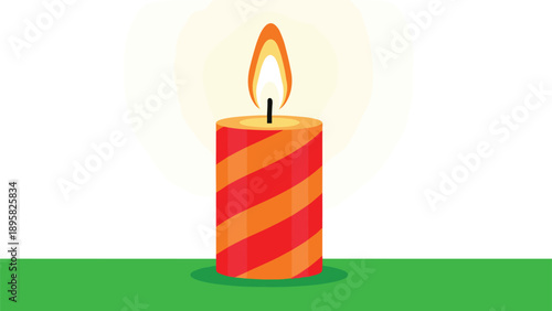 Festive lit candle with red and orange diagonal stripes burning with a bright yellow flame on a green surface.