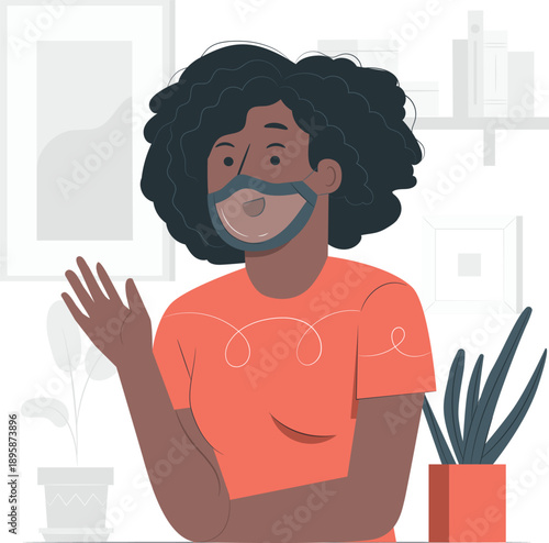 A woman with curly hair smiling and greeting someone in a room with a plant nearby, conveying a sense of friendliness and warmth indoors.