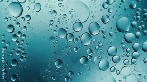 A close-up showcases numerous, translucent, water-like orbs, varying in size, set against a gradient of teal hues. The bubbles have high reflectivity