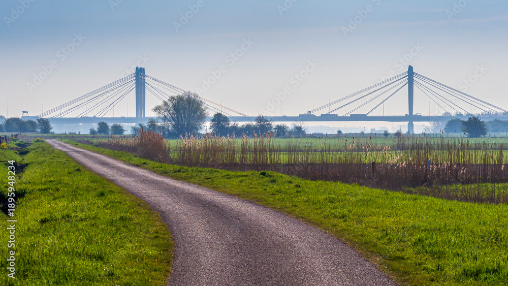 Fototapeta premium Rural road leading to cable stayed Tacitus bridge