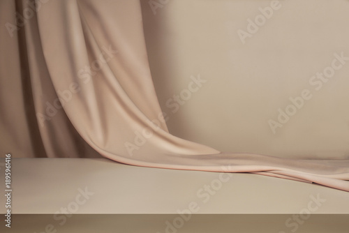 A minimalist beige background with a pedestal and hanging fabric. A backdrop for objects.