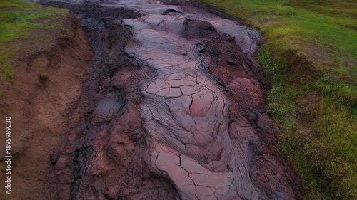 Muddy road through green landscape aerial.