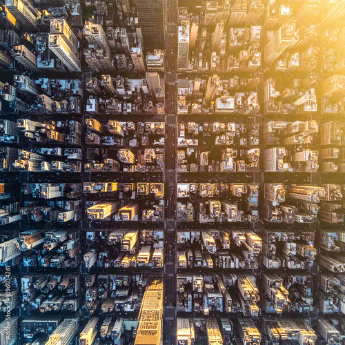 An impressive aerial topdown view of a dense urban cityscape at sunset. Golden light illuminates the skyscrapers and grid streets, ideal for business, real estate, and travel projects.