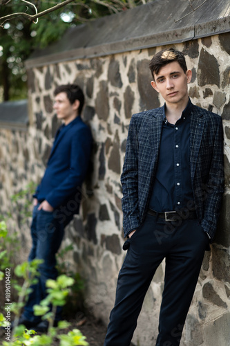 Εκτύπωση καμβά Young men stand against a stone wall during the day in an outdoor location while