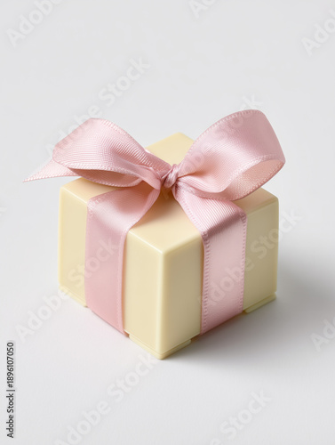 A luxurious and minimal gift box made entirely of creamy white chocolate, elegantly tied with a soft pink satin ribbon and bow, isolated on a white background.