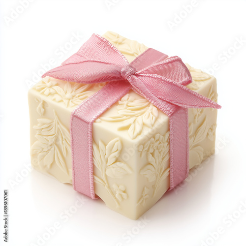 A luxurious and minimal gift box made entirely of creamy white chocolate, elegantly tied with a soft pink satin ribbon and bow, isolated on a white background.
