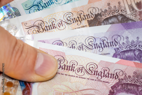 British pounds held in hand, macro close-up, Bank of England text. Close up