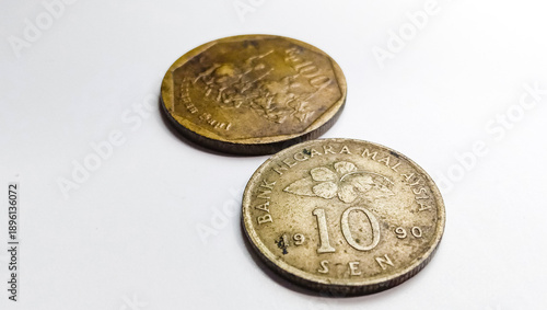 Perspective view of vintage Malaysia 10 Cent and Indonesia 100 Rupiah coins isolated on white background.