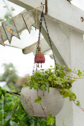 Planter hanging from a structure with green plants in a garden setting