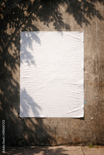 Blank white poster paper glued on a weathered grey concrete wall mockup with urban street shadows.