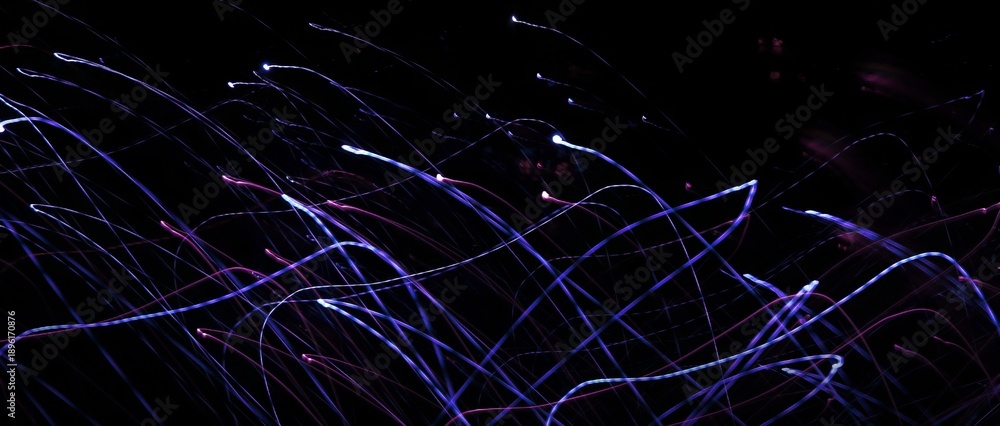Naklejka premium Night photography with selective focus and long exposure. Linear composition in motion. Abstract background, glowing lines. Copy space. Textures of light. Wrapper. Backing. Cover. A unique image.