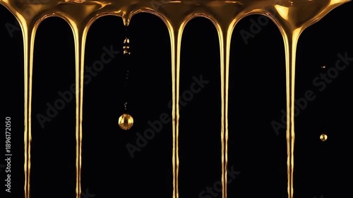 Golden liquid dripping slowly on a black background, creating a mesmerizing and luxurious visual effect.