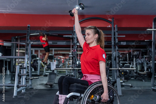 Woman in a wheelchair lifting weight in gym