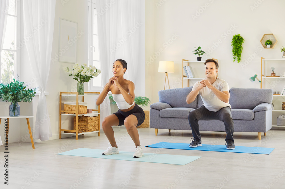 Fototapeta premium Couple family workout at home together. They practice exercise with squats and light cardio on mats, training legs, staying healthy and boosting fitness. Shared goals nurture a strong bond.