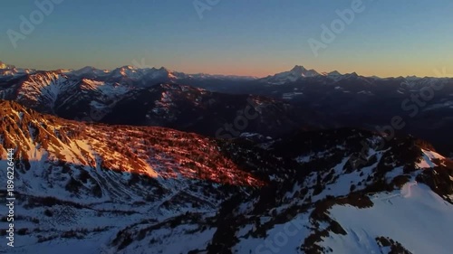 Snow covered mountains at sunset with orange and blue hues