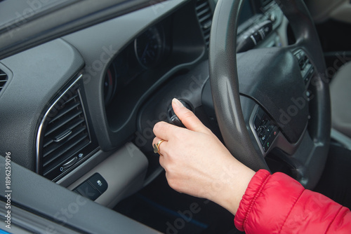 Female hand is adjusting headlight switch in car.