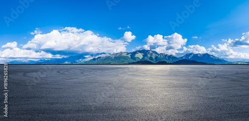 Wallpaper Mural An empty asphalt road and tire tracks with a beautiful mountain landscape under a blue sky and white clouds Torontodigital.ca